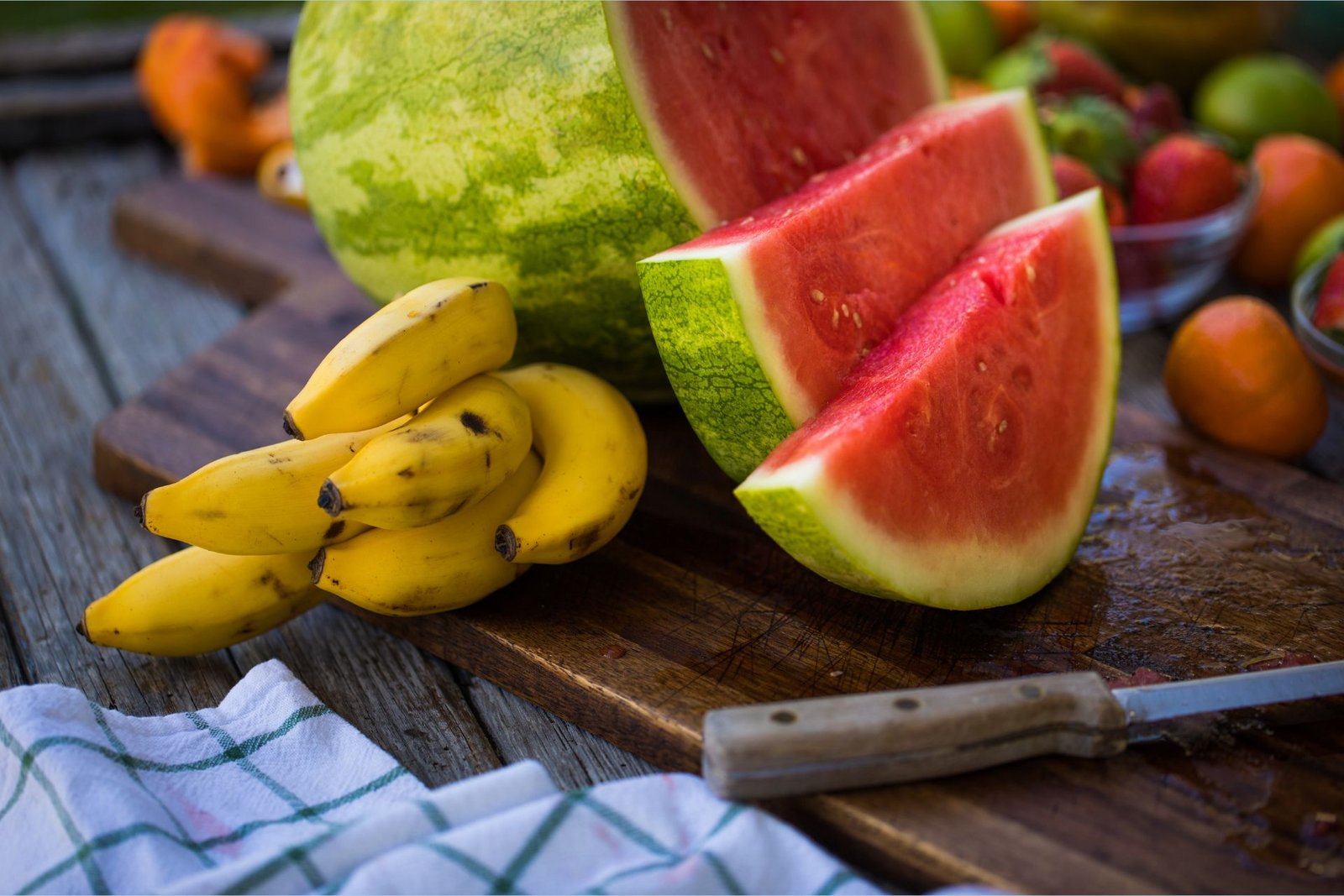 Kaliumrige bananer ligger ved siden af en L-citrullinrig skiveskåret vandmelon på et skærebræt